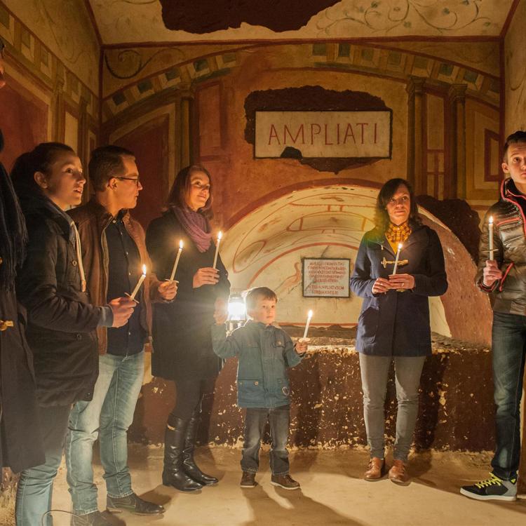 Personen met kaarsjes tijdens een rondleiding door de Romeinse Katakomben in Valkenburg