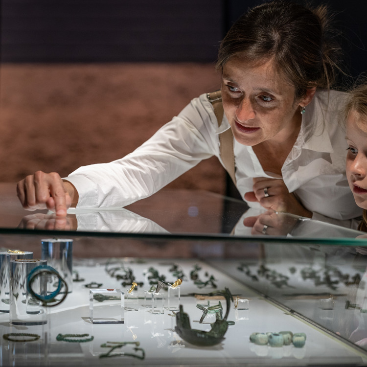 Mevrouw met kindje bekijken een vitrine met Romeinse vondsten in het Romeins Museum Heerlen